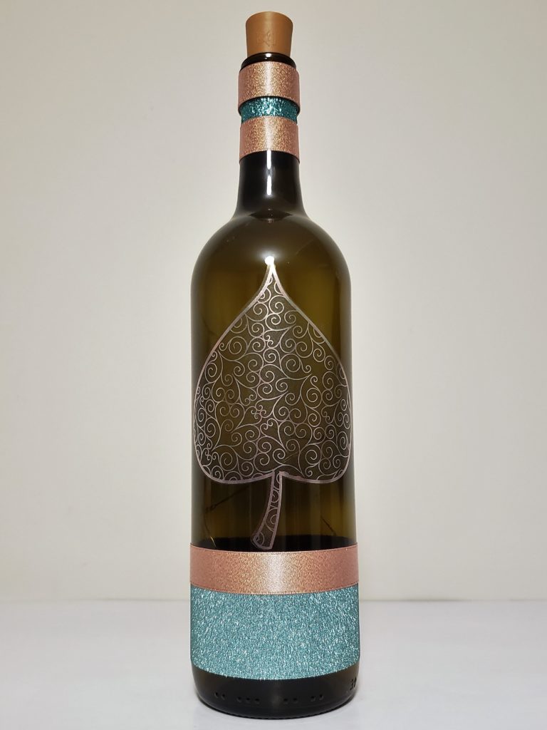 Bottle light with a metallic spade leaf and teal and pink bottom.