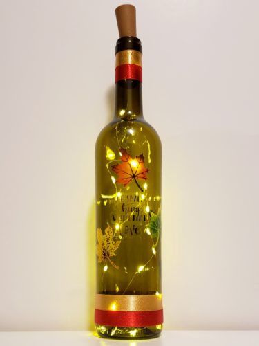 Bottle light with "Do small things with great love" surrounded by three fall leaves.